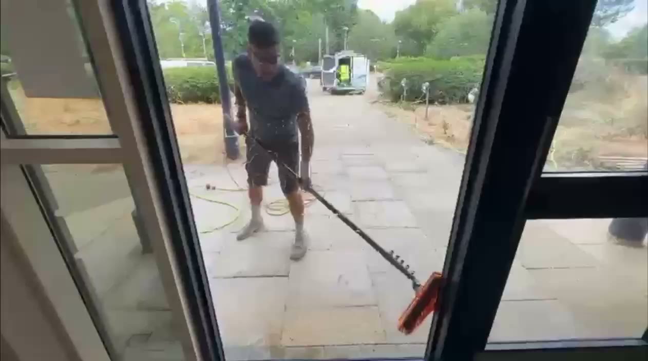 Water-fed pole and brush cleaning an upper-floor window