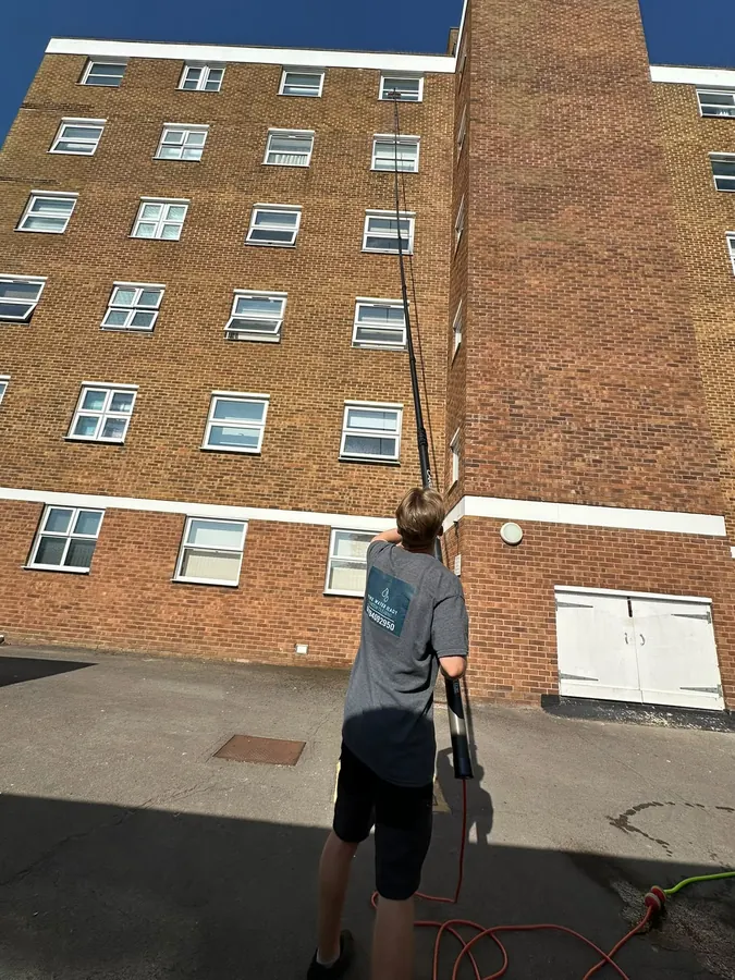 A team member reaching the upper floors of a large apartment block with the water-fed pole