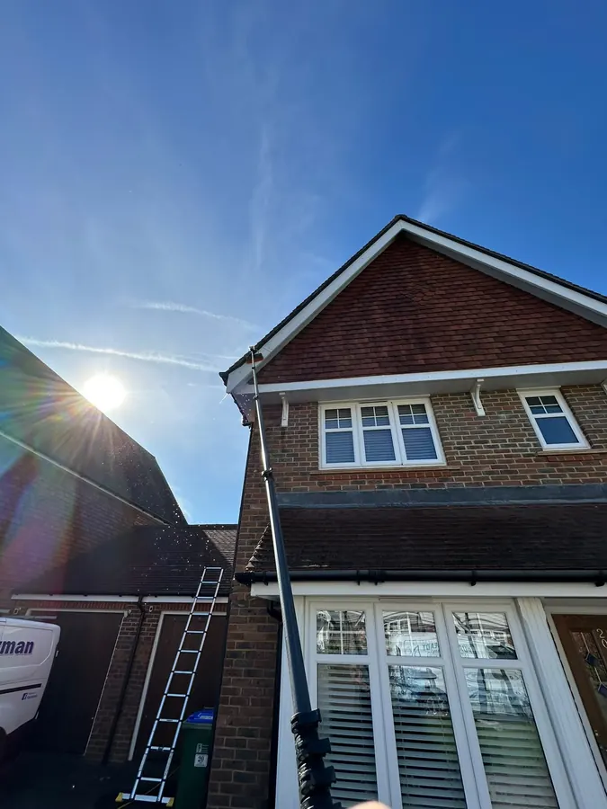 Water-fed pole reaching high on a large detached home in bright sunshine