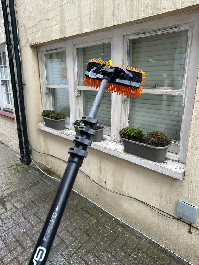 Water-fed pole cleaning sash windows on a period shopfront